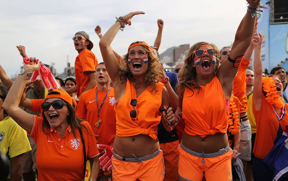 Soccer fans, decked out in orange, the Netherlands' national color, celebrate their side's second goal scored by Memphis Depay, while watching a live broadcast of the group B World Cup match between Chile and Netherlands, inside the FIFA Fan Fest area on Copacabana beach, in Rio de Janeiro, Brazil.