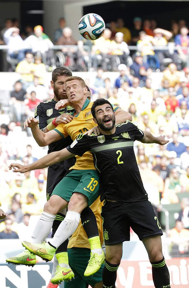 Spain's Sergio Ramos, left, Australia's Oliver Bozanic and Spain's Raul Albiol go for a header during the group B World Cup soccer match between Australia and Spain at the Arena da Baixada in Curitiba, Brazil.