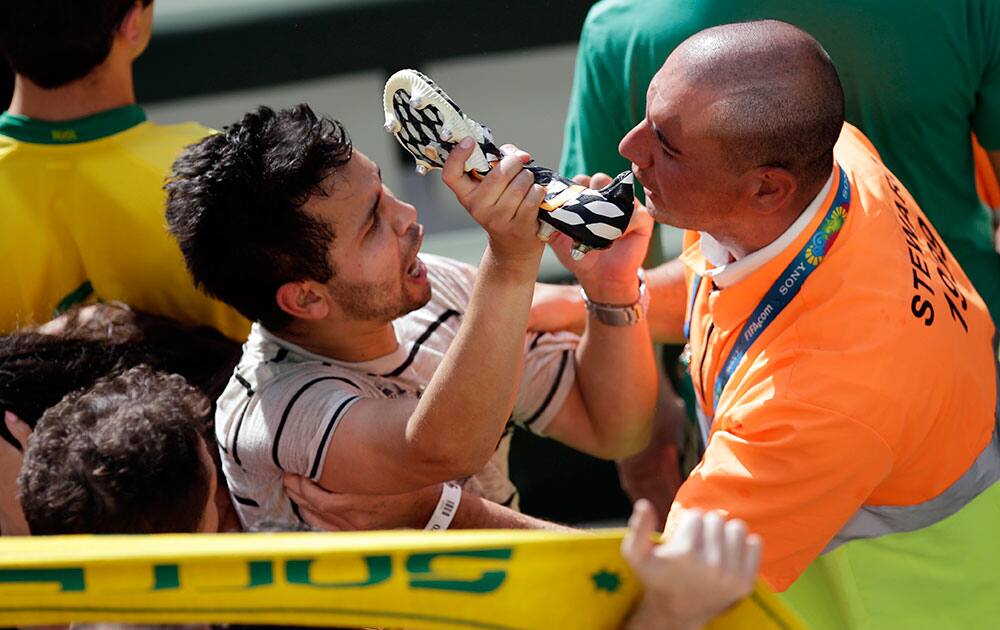 A spectator holds up a boot that he caught when Spain's goalkeeper Iker Casillas threw it into the crowd as he left the field after the group B World Cup soccer match between Australia and Spain at the Arena da Baixada in Curitiba, Brazil.