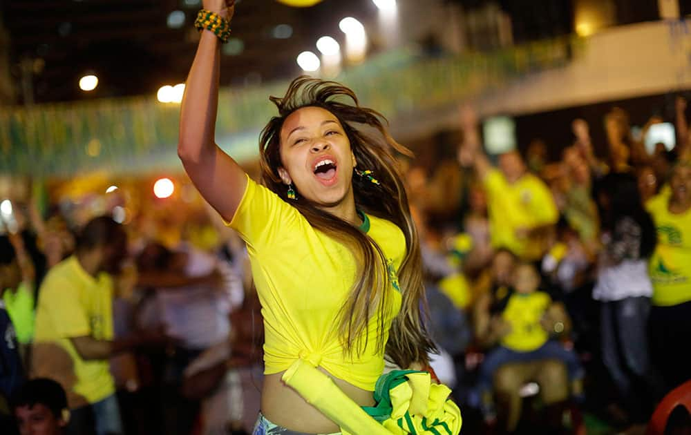 A Brazilian soccer fan celebrates after Brazil scored against Cameroon, while watching the match on a giant television screen in Bixiga neighborhood in Sao Paulo, Brazil.