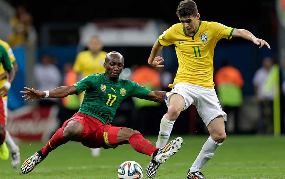 Cameroon's Stephane Mbia, left, and Brazil's Oscar challenge for the ball during the group A World Cup soccer match between Cameroon and Brazil at the Estadio Nacional in Brasilia, Brazil.