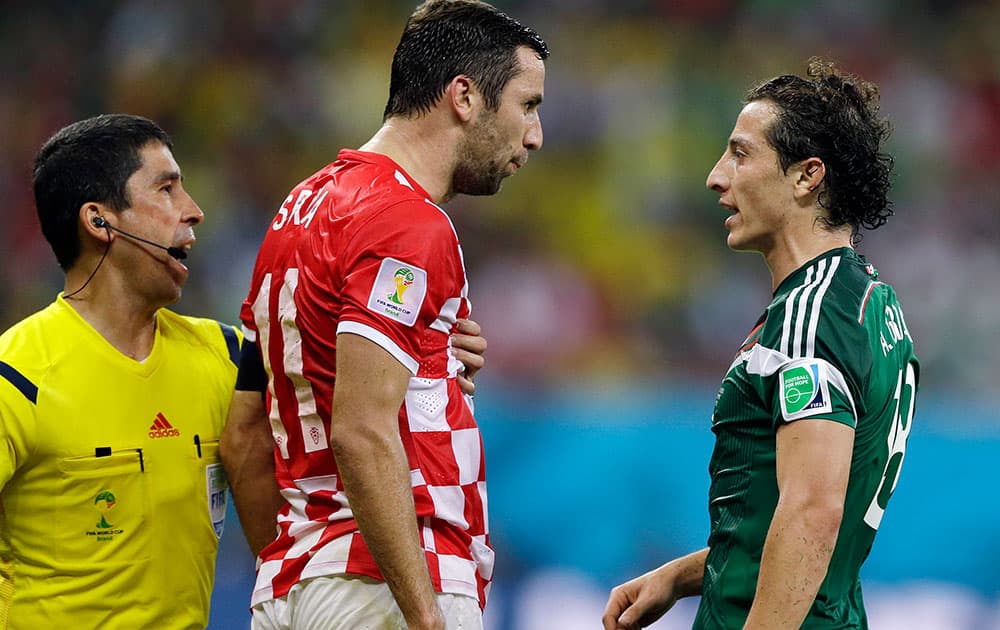 A linesman tries to prevent Croatia's Darijo Srna, center, from clashing with Mexico's Andres Guardado during the group A World Cup soccer match between Croatia and Mexico at the Arena Pernambuco in Recife, Brazil.