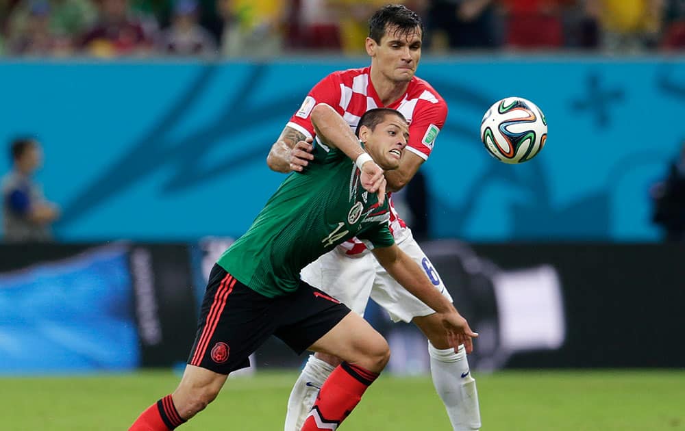 Mexico's Javier Hernandez, front, is held back by Croatia's Dejan Lovren during the group A World Cup soccer match between Croatia and Mexico at the Arena Pernambuco in Recife, Brazil.