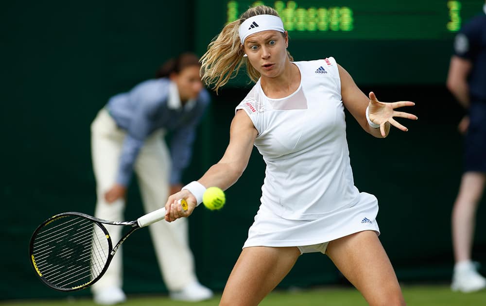 Stefanie Voegele of Switzerland plays a return to Jarmila Gajdosova of Australia during their first round match at the All England Lawn Tennis Championships in Wimbledon, London