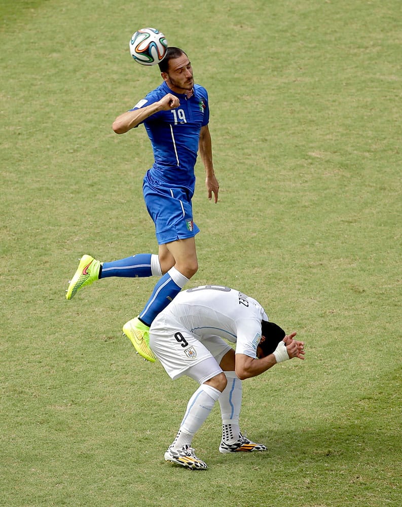 Italy's Leonardo Bonucci (19) goes up against Uruguay's Luis Suarez (9) during the group D World Cup soccer match between Italy and Uruguay at the Arena das Dunas in Natal, Brazil.