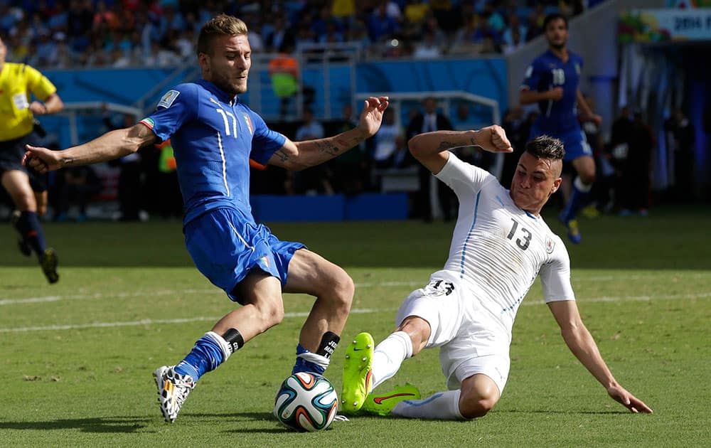 Italy's Ciro Immobile, left, is challenged by Uruguay's Jose Maria Gimenez during the group D World Cup soccer match between Italy and Uruguay at the Arena das Dunas in Natal, Brazil.