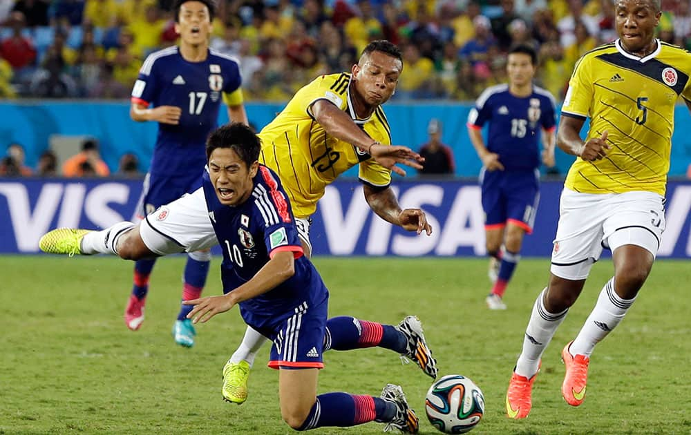 Japan's Shinji Kagawa, front, brings down Colombia's James Rodriguez during the group C World Cup soccer match between Japan and Colombia at the Arena Pantanal in Cuiaba, Brazil.