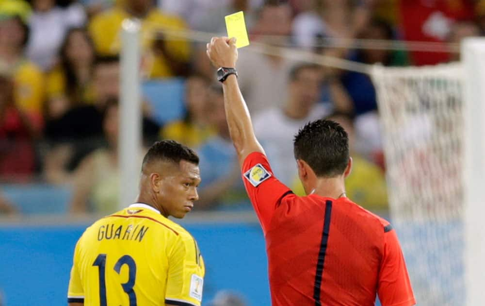 Colombia's Fredy Guarin get yellow-carded by Pedro Proenca, from Portugal, during the group C World Cup soccer match between Japan and Colombia at the Arena Pantanal in Cuiaba, Brazil.