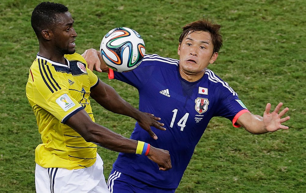 Japan midfielder Toshihiro Aoyama, right, heads the ball away defender from Colombia during the second half of a group C World Cup soccer match at the Arena Pantanal in Cuiaba, Brazil.