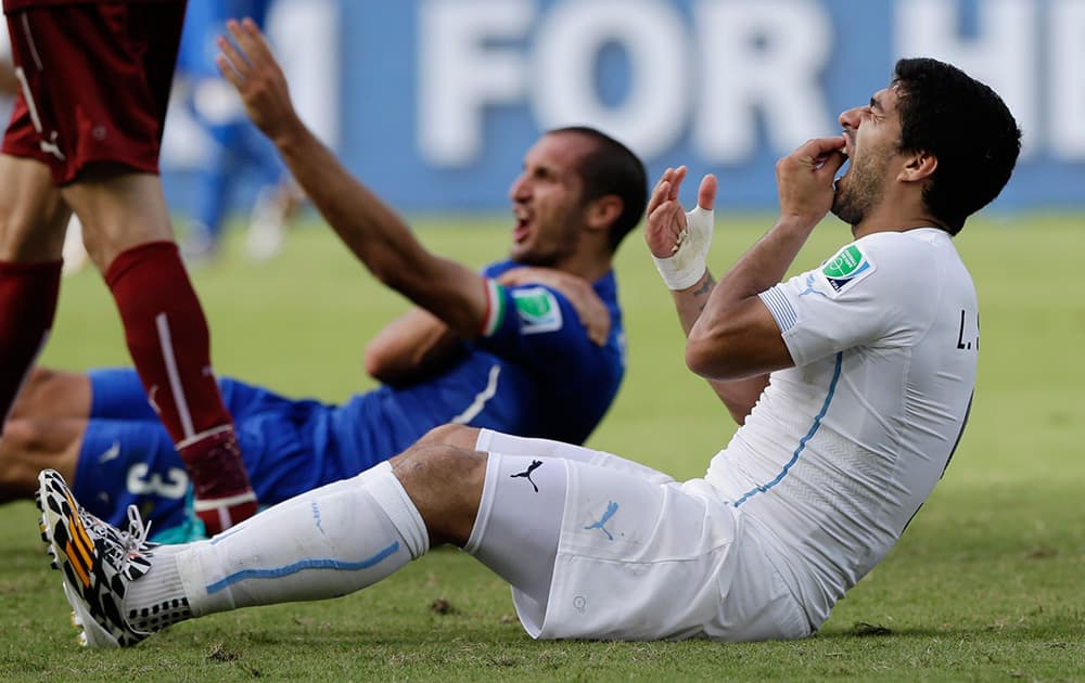 Uruguay's Luis Suarez holds his teeth after running into Italy's Giorgio Chiellini's shoulder during the group D World Cup soccer match between Italy and Uruguay at the Arena das Dunas in Natal, Brazil.