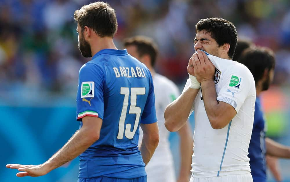 Uruguay's Luis Suarez holds his teeth after running into Italy's Giorgio Chiellini's shoulder during the group D World Cup soccer match between Italy and Uruguay at the Arena das Dunas in Natal, Brazil.