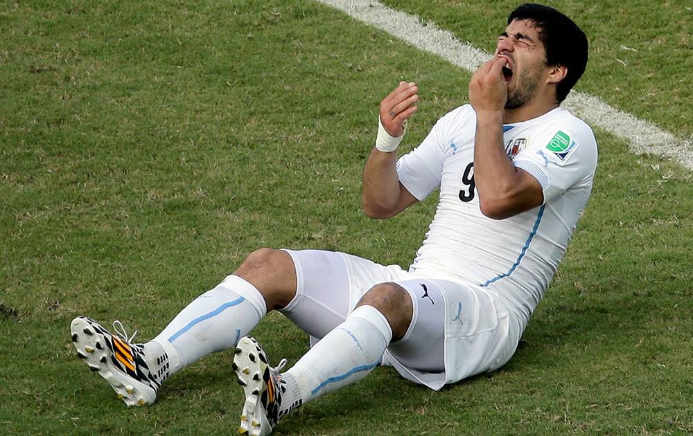 Uruguay's Luis Suarez (9) holds his teeth after running into Italy's Giorgio Chiellini's shoulder during the group D World Cup soccer match between Italy and Uruguay at the Arena das Dunas in Natal, Brazil.