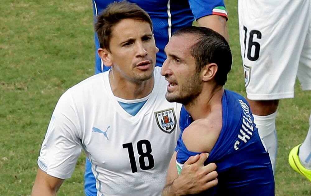 Italy's Giorgio Chiellini shows his shoulder after colliding with Uruguay's Luis Suarez's mouth as Uruguay's Gaston Ramirez (18) watches during the group D World Cup soccer match between Italy and Uruguay at the Arena das Dunas in Natal, Brazil.