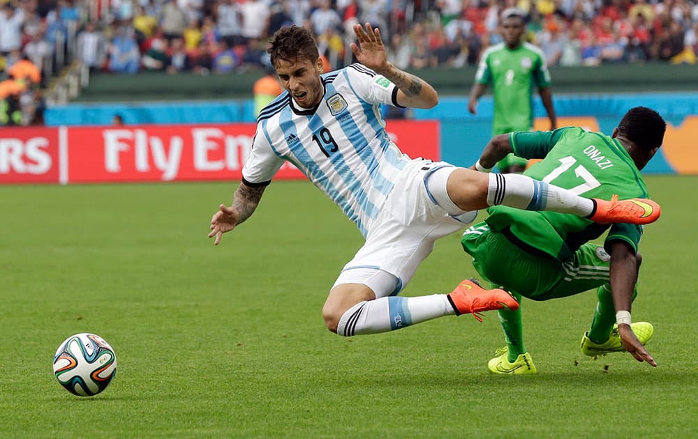 Argentina's Ricardo Alvarez falls over Nigeria's Ogenyi Onazi, right, during the group F World Cup soccer match between Nigeria and Argentina at the Estadio Beira-Rio in Porto Alegre, Brazil.