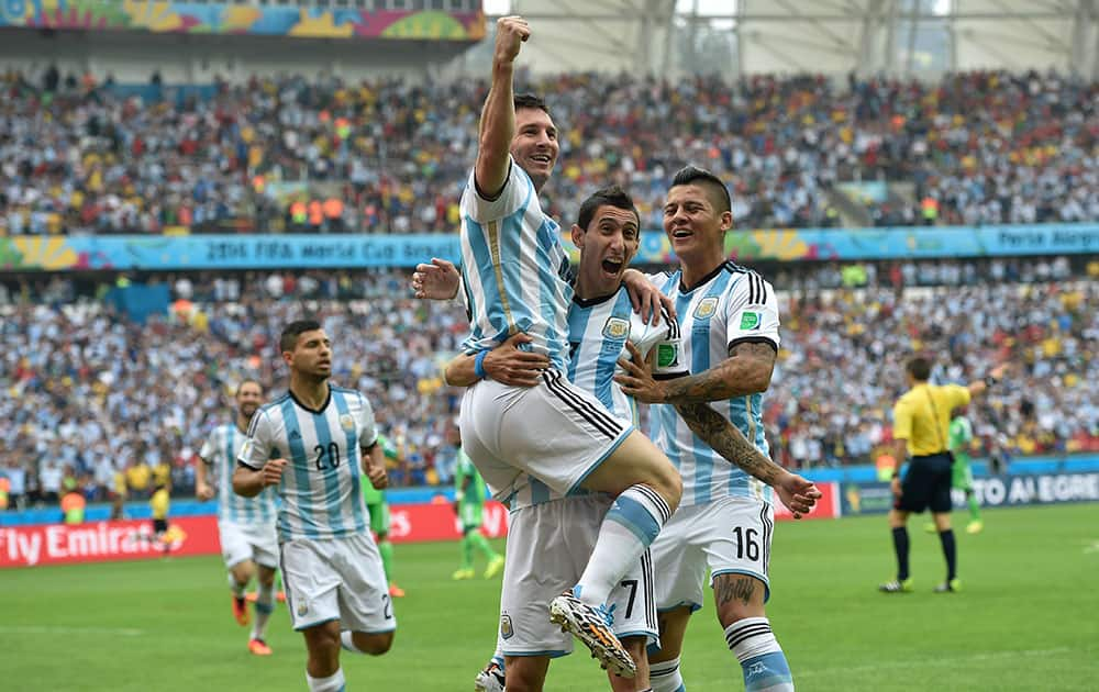 Argentina's Lionel Messi, left, is carried by his teammates Argentina's Angel di Maria (7) and Argentina's Marcos Rojo after scoring his side's first goal during the group F World Cup soccer match between Nigeria and Argentina at the Estadio Beira-Rio in Porto Alegre, Brazil.