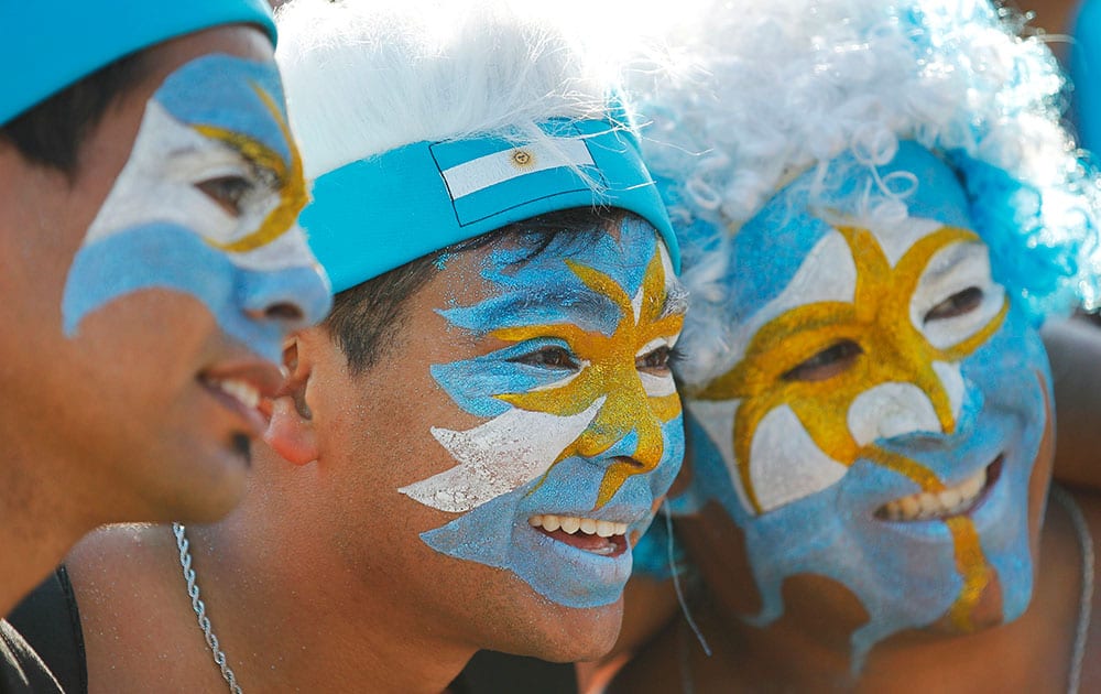 Argentina soccer fans, their faces painted to represent their country's national flag, pose for a photo during a live telecast of the World Cup group F match between Nigeria and Argentina, inside the FIFA Fan Fest area on Copacabana beach, in Rio de Janeiro, Brazil.