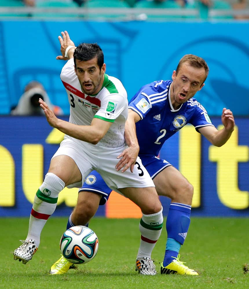 Iran's Ehsan Haji Safi, left, and Bosnia's Avdija Vrsajevic vie for the ball during the group F World Cup soccer match between Bosnia and Iran at the Arena Fonte Nova in Salvador, Brazil.