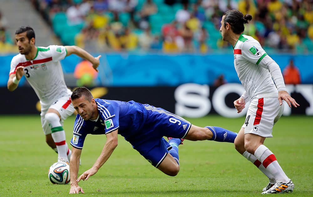 Bosnia's Vedad Ibisevic, center, is tripped by Iran's Andranik Teymourian, right, during the group F World Cup soccer match between Bosnia and Iran at the Arena Fonte Nova in Salvador, Brazil.