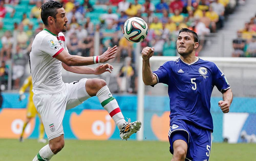 Iran's Reza Ghoochannejhad, left, fights for the ball with Bosnia's Sead Kolasinac during the group F World Cup soccer match between Bosnia and Iran at the Arena Fonte Nova in Salvador, Brazil.