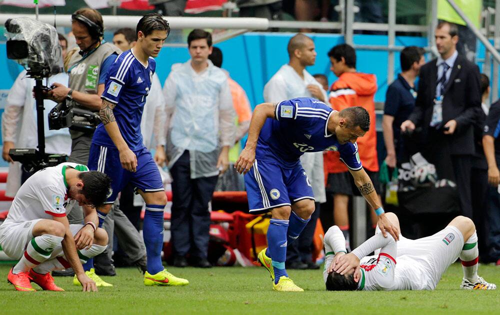 Iranian players are consoled by Bosnian players after the group F World Cup soccer match between Bosnia and Iran at the Arena Fonte Nova in Salvador, Brazil.