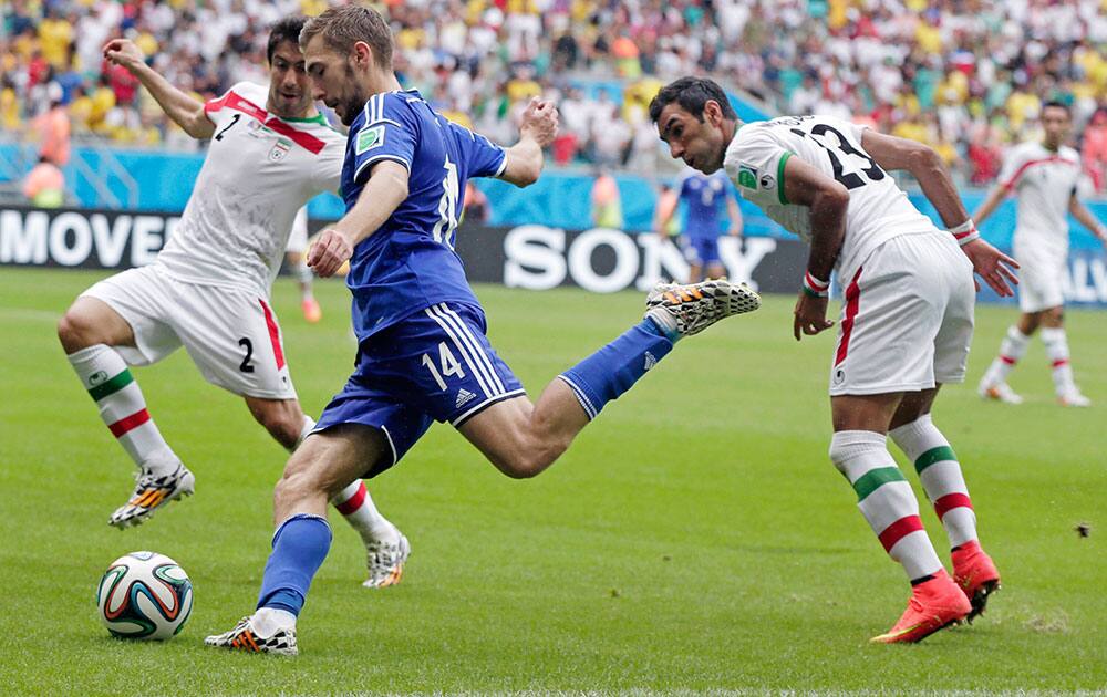 Bosnia's Tino-Sven Susic shoots a cross past Iran's Khosro Heydari, left, during the group F World Cup soccer match between Bosnia and Iran at the Arena Fonte Nova in Salvador, Brazil.