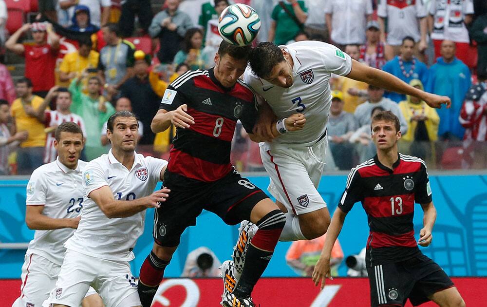 Germany's Mesut Ozil, center, goes for a header with United States' Omar Gonzalez as United States' Graham Zusi, left, looks on during the group G World Cup soccer match between the USA and Germany at the Arena Pernambuco in Recife, Brazil.