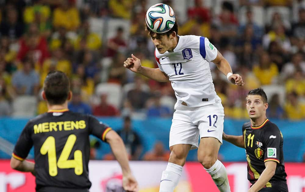 South Korea's Lee Yong heads a ball as Belgium's Dries Mertens, left, and Kevin Mirallas look on during the group H World Cup soccer match between South Korea and Belgium at the Itaquerao Stadium in Sao Paulo, Brazil.