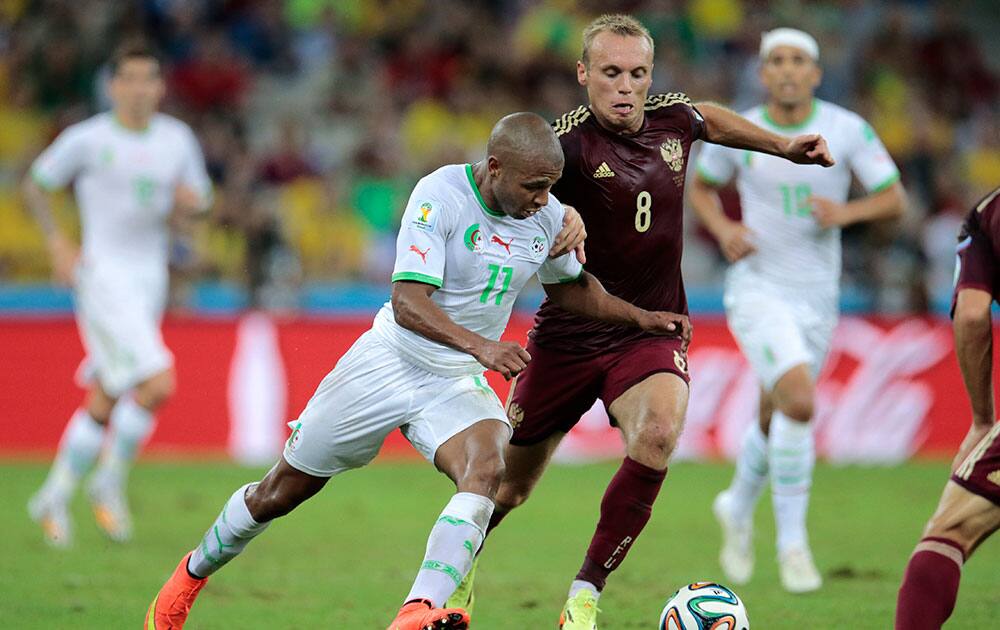 Algeria's Yacine Brahimi is challenged by Russia's Denis Glushakov, right, during the group H World Cup soccer match between Algeria and Russia at the Arena da Baixada in Curitiba, Brazil.