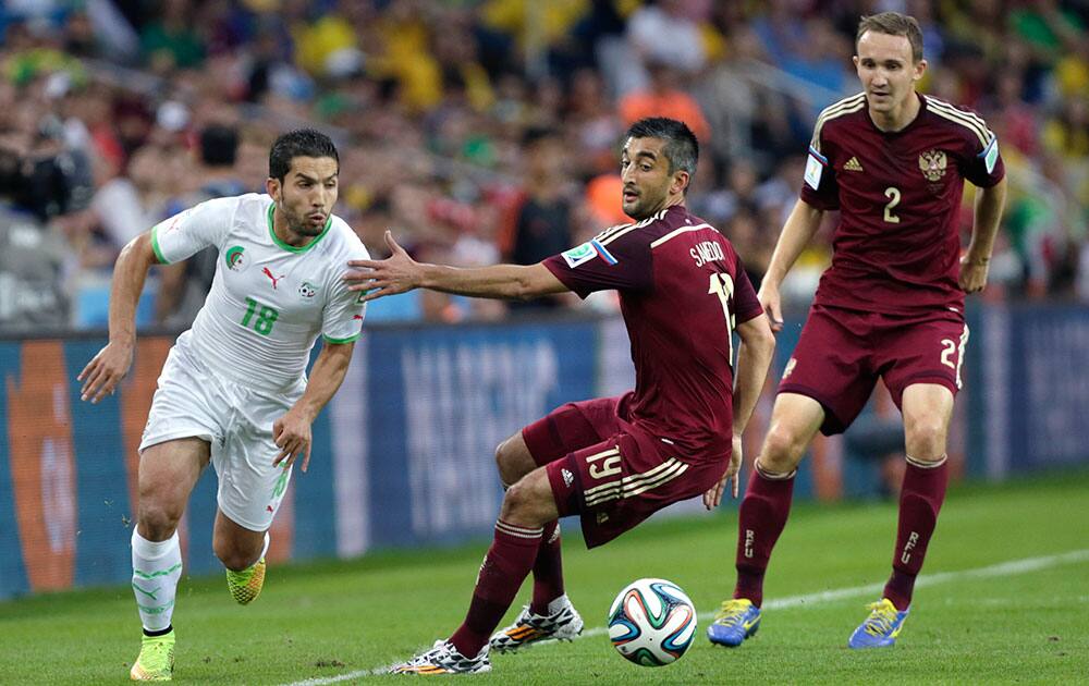 Algeria's Abdelmoumene Djabou, left, runs past Russia's Alexander Samedov with the ball during the group H World Cup soccer match between Algeria and Russia at the Arena da Baixada in Curitiba, Brazil.