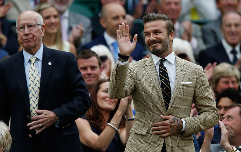 Former English soccer player David Beckham waves as he stands next to former English soccer player Sir Bobby Charlton at the Royal Box on centre court at the All England Lawn Tennis Championships in Wimbledon, London.