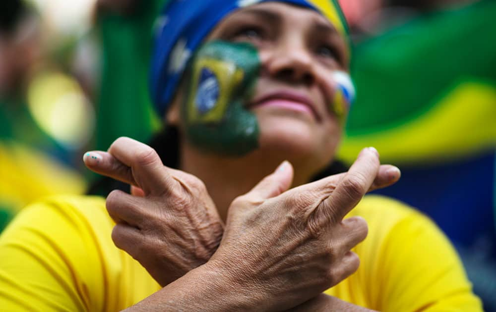 A Brazil soccer fan crosses her fingers as she watches a live telecast of the World Cup round of 16 match between Brazil and Chile inside the FIFA Fan Fest area in Sao Paulo, Brazil.