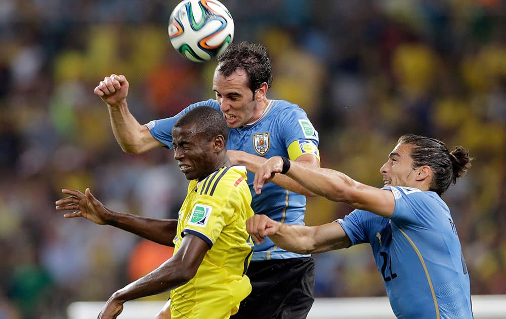 Uruguay's Diego Godin, center, goes for a header with Colombia's Adrian Ramos, left, and Uruguay's Martin Caceres during the World Cup round of 16 soccer match between Colombia and Uruguay at the Maracana Stadium in Rio de Janeiro, Brazil.