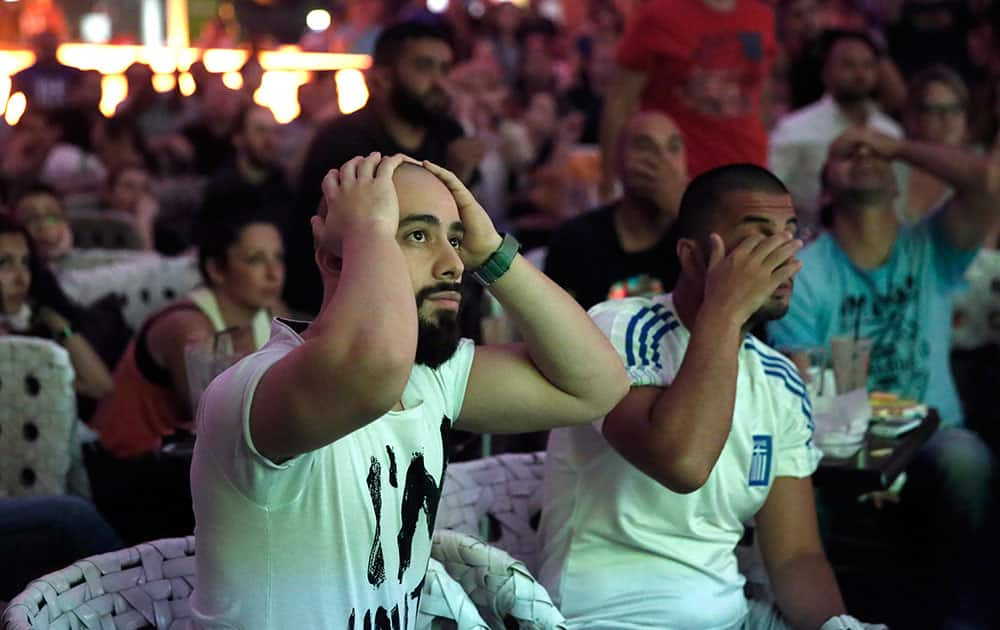 Greece's soccer fans react as they watch a World Cup match between Greece and Costa Rica via a live broadcast on a giant screen, at a mall in Athens, Greece.