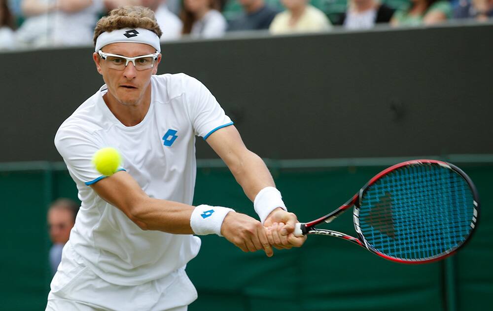 Denis Istomin of Uzbekistan plays a return to Stan Wawrinka of Switzerland during their men's singles match at the All England Lawn Tennis Championships in Wimbledon.