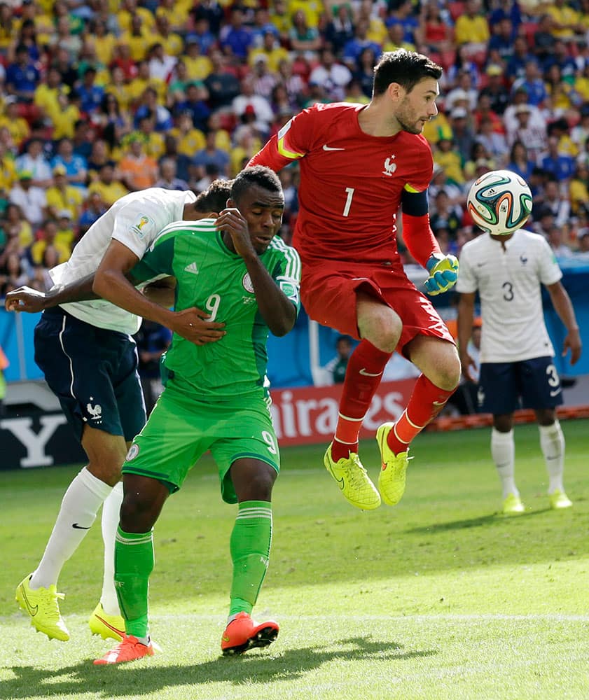 France's goalkeeper Hugo Lloris, center, leaps in front of Nigeria's Emmanuel Emenike to make a save during the World Cup round of 16 soccer match between France and Nigeria at the Estadio Nacional in Brasilia, Brazil.