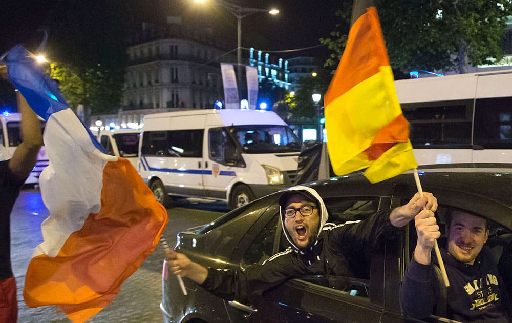 French soccer fans wave a French and a German national flag after France won 2-0 against Nigeria at the Champs Elysees avenue in Paris.