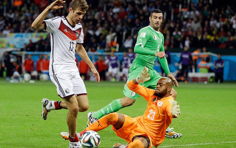 Algeria's goalkeeper Rais M’Bolhi (23) slides in to stop a shot by Germany's Thomas Mueller (13) during the World Cup round of 16 soccer match between Germany and Algeria at the Estadio Beira-Rio in Porto Alegre, Brazil.