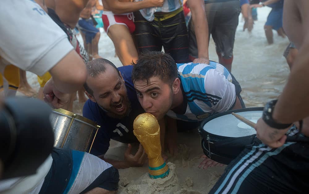 Argentina soccer fans kiss a replica of the World Cup trophy after their team's victory at a World Cup match with Switzerland on Copacabana beach in Rio de Janeiro, Brazil.