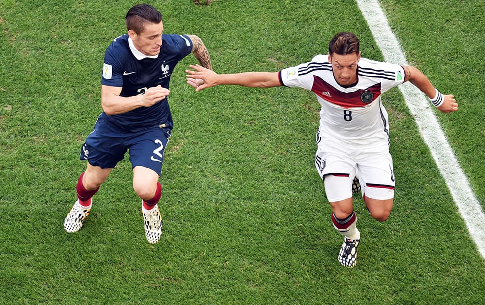 Germany's Mesut Ozil, right, holds off France's Mathieu Debuchy during the World Cup quarterfinal soccer match at the Maracana Stadium in Rio de Janeiro, Brazil.