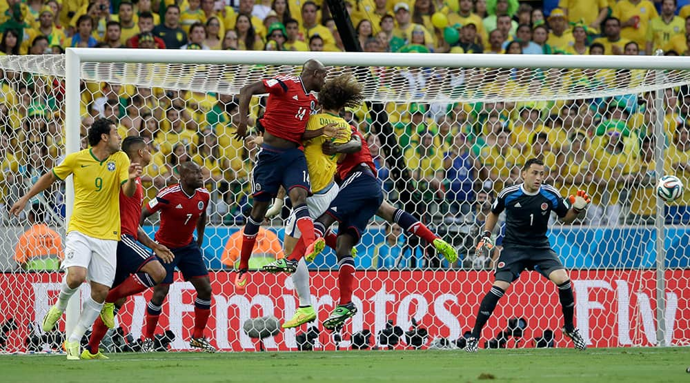 Brazil's David Luiz jumps between Colombia's defenders as the ball crosses in front of Colombia's goalkeeper David Ospina during the World Cup quarterfinal soccer match between Brazil and Colombia at the Arena Castelao in Fortaleza, Brazil.