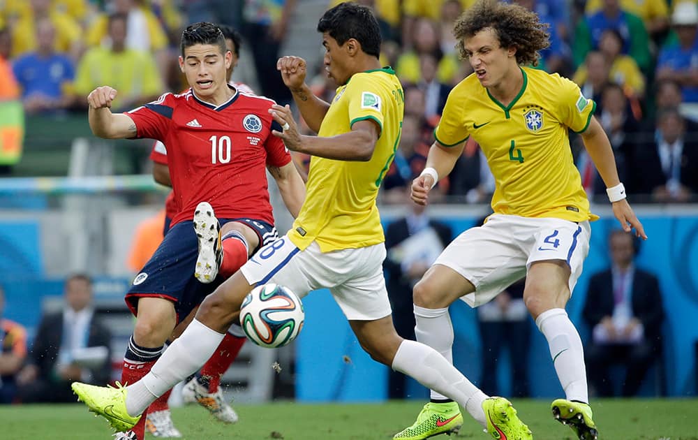 Colombia's James Rodriguez kicks the ball past Brazil's Hernanes as Brazil's David Luiz looks on during the World Cup quarterfinal soccer match between Brazil and Colombia at the Arena Castelao in Fortaleza, Brazil.