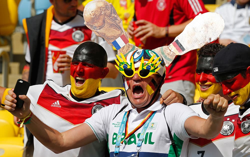 A man with stickers of both the French and the German flags on replicas of the World Cup trophy poses for pictures with Germany's fans before the World Cup quarterfinal soccer match between Germany and France at the Maracana Stadium in Rio de Janeiro, Brazil.