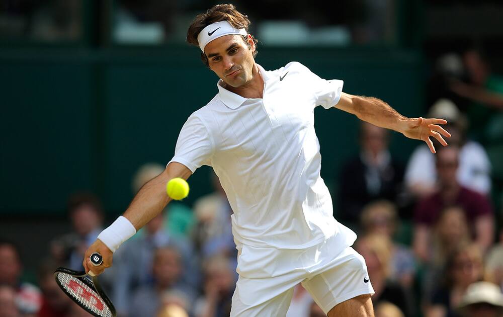 Roger Federer of Switzerland plays a return to Milos Raonic of Canada during their men’s singles semifinal match at the All England Lawn Tennis Championships in Wimbledon.