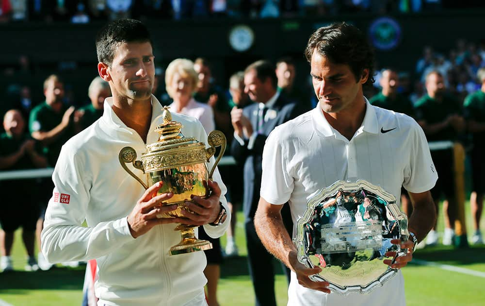 Serbia's Novak Djokovic, left, holds his trophy after defeating Switzerland's Roger Federer, right, in the men's singles final match at the All England Lawn Tennis Championships in Wimbledon.