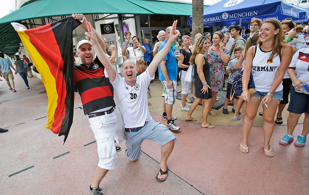 Ulf Roentgen, left, on vacation from Cologne, Germany, waves a German flag as he and Frank Neupert of Erfurt, Germany, celebrate Germany's win against Brazil during the World Cup semi final, after having watched the match outside the Hofbrau Beer Hall, in Miami Beach, Fla. 