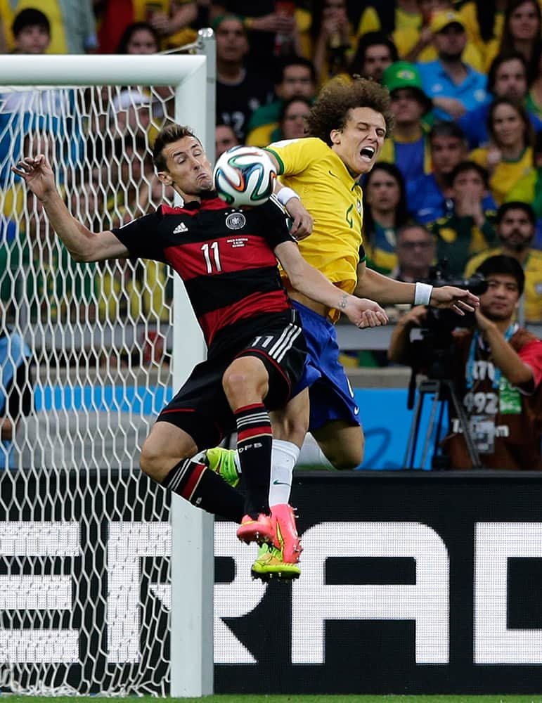 Germany's Miroslav Klose, left, and Brazil's David Luiz battle for the ball during the World Cup semifinal soccer match between Brazil and Germany at the Mineirao Stadium in Belo Horizonte, Brazil.