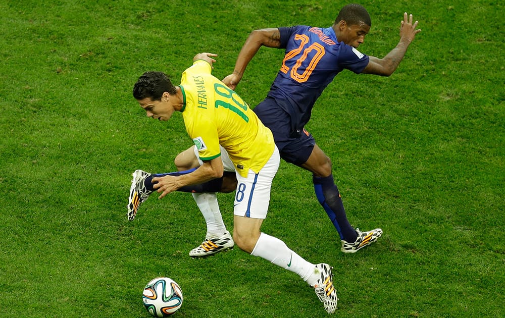 Brazil's Hernanes and Netherlands' Georginio Wijnaldum fight for the ball during the World Cup third-place soccer match between Brazil and the Netherlands at the Estadio Nacional in Brasilia, Brazil.