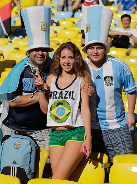 Argentine fans pose next to a Brazilian fan, center, before the start of the World Cup final soccer match between Germany and Argentina at the Maracana Stadium in Rio de Janeiro, Brazil.