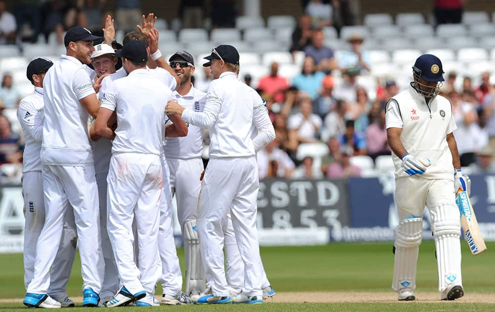 India captain M. S. Dhoni, right, walks back to the pavilion while England players celebrate, after being bowled by England's Liam Plunkett for 11 runs during day five of the first Test between England and India at Trent Bridge cricket ground, Nottingham, England.