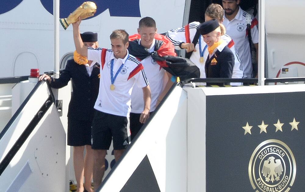 German national soccer players from left: Philipp Lahm Bastian Schweinsteiger ,Thomas Mueller and Sami Khedira, arrive with the trophy at Tegel airport in Berlin.